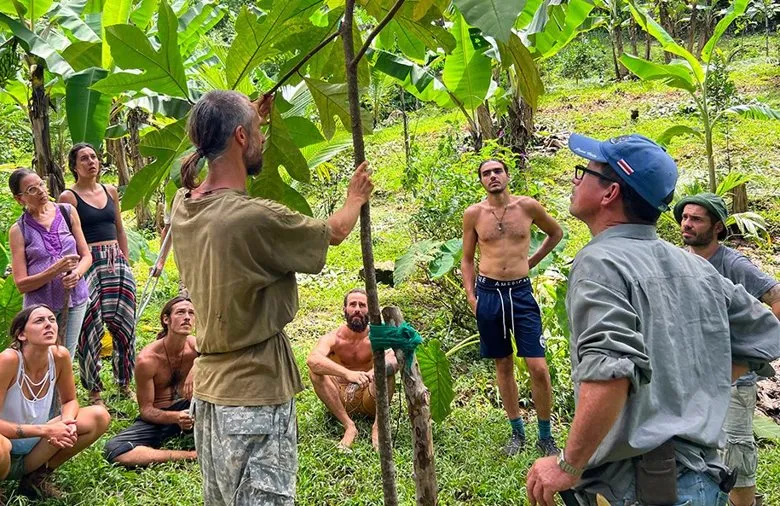 Travis leading a hands-on agroforestry training with a group in a food forest